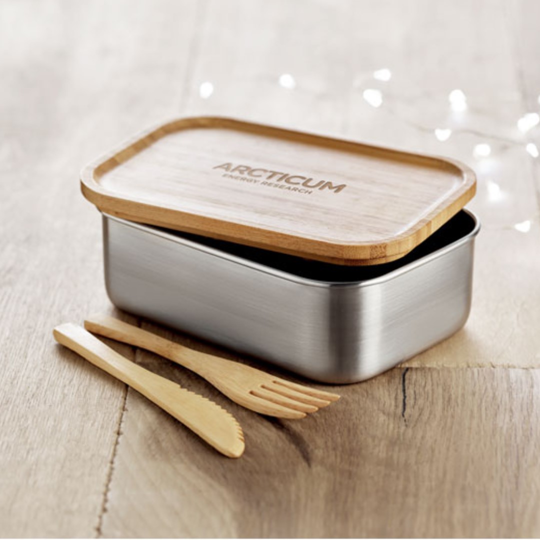 Lunchbox with logo SAVANNA Stainless Steel lunchbox with logo and bamboo lid. 2 Cutlery utensils with attachable polyester band. Capacity 600ml. Bamboo is a natural product, there may be slight variations in colour and size per item, which can affect the final decoration outcome. We use different printing techniques to add your logo. Depending on the surface we can use embroidery, engraving, 360° imprint or screenprint.