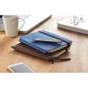 Notebook with logo SOFTNOTE A5 Notebook with logo and soft PU cover. Casebound. 160 lined pages (80 sheets). Matching elastic closure strap and ribbon bookmark. Expandable inner pocket in the back. Pen holder in the spine. Depending on the surface we can use embroidery, engraving, 360° imprint or screen print.