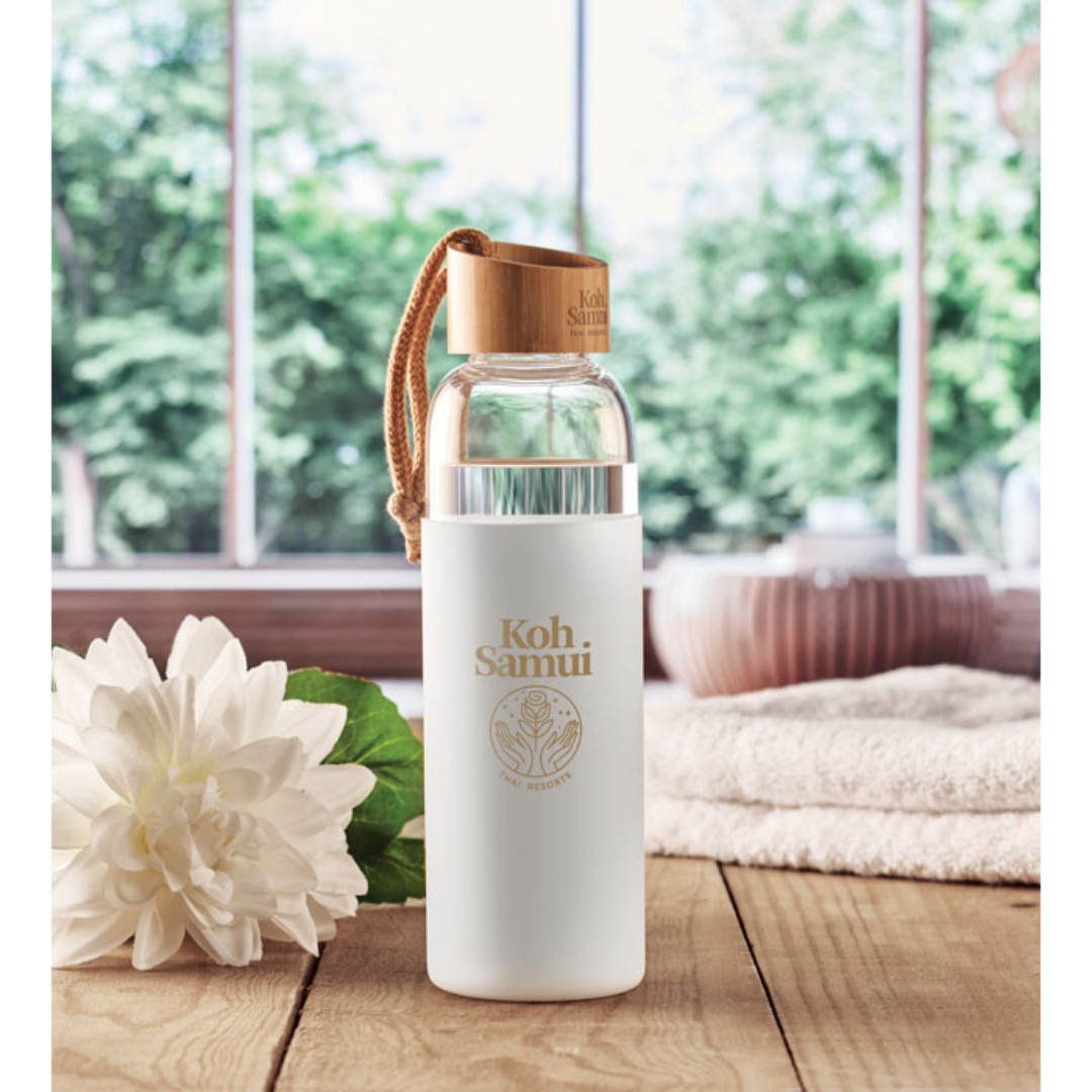Water bottle with logo CHAI Gadget water bottle with logo in glass with silicone pouch. Bamboo lid with cotton wrist loop. Not suitable for carbonated drinks. Leak free. Capacity: 500 ml. Magnus Business Gifts is your partner for merchandising, gadgets or unique business gifts since 1967. Certified with Ecovadis gold!